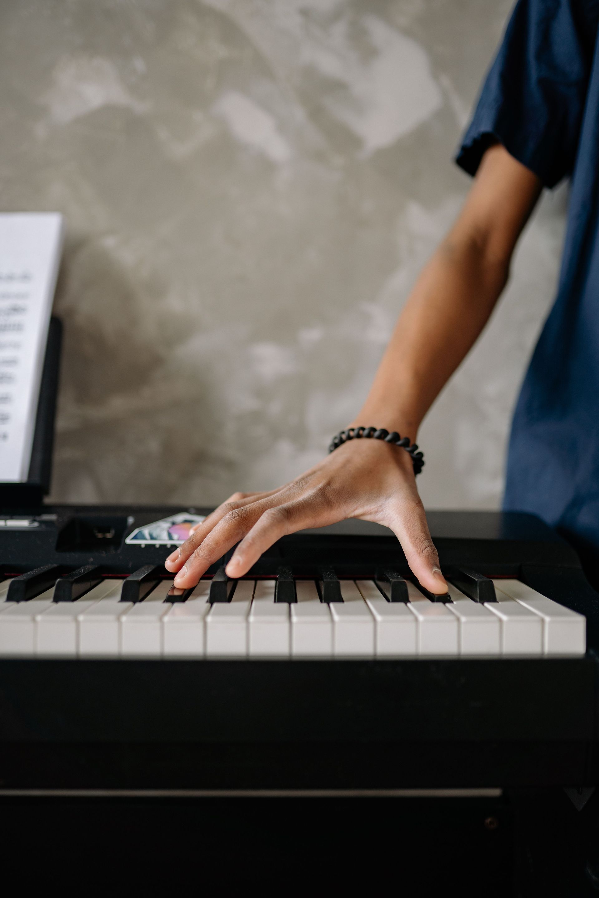 Close-up of a person's hand playing piano keys, indoor setting.